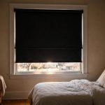 energy efficient blackout roller shades for sale: Blackout roller shade blocks light in a bedroom window