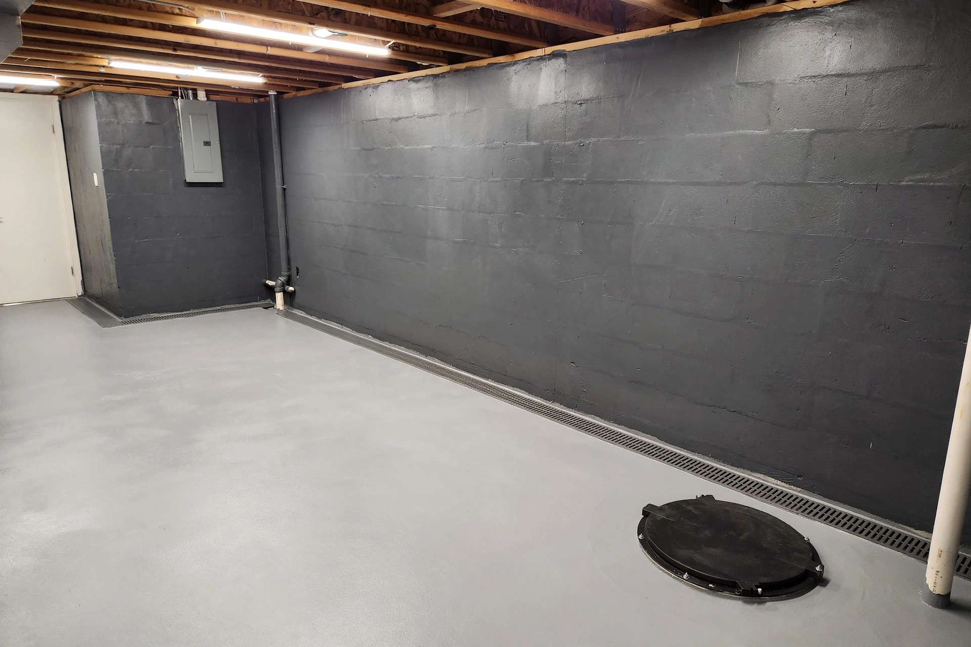 Dry basement wall with drainage system after premium basement waterproofing services for homeowners