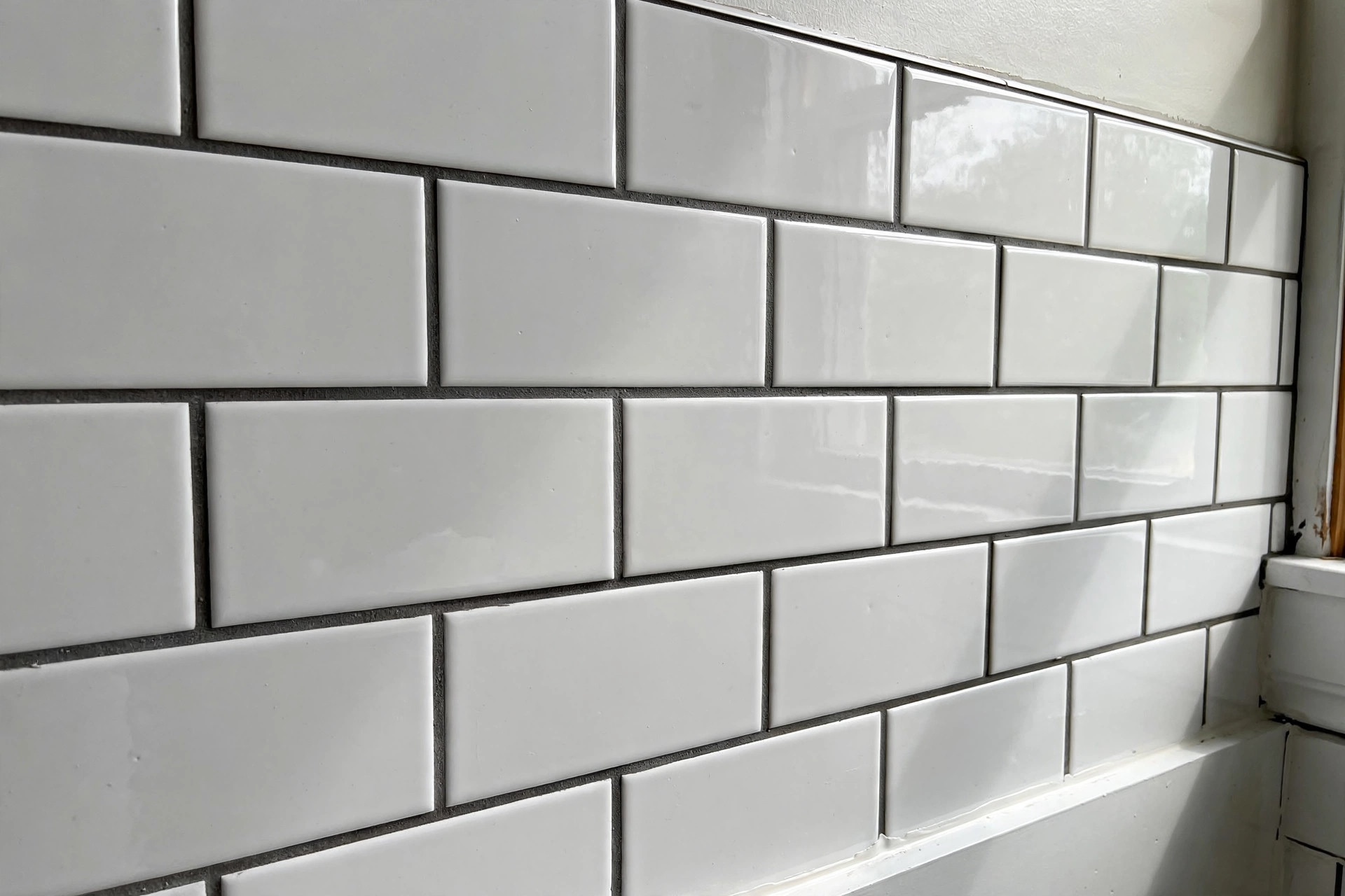 epoxy grout vs cement grout comparison usa: Newly grouted white subway tile wall with dark grout lines in an American bathroom