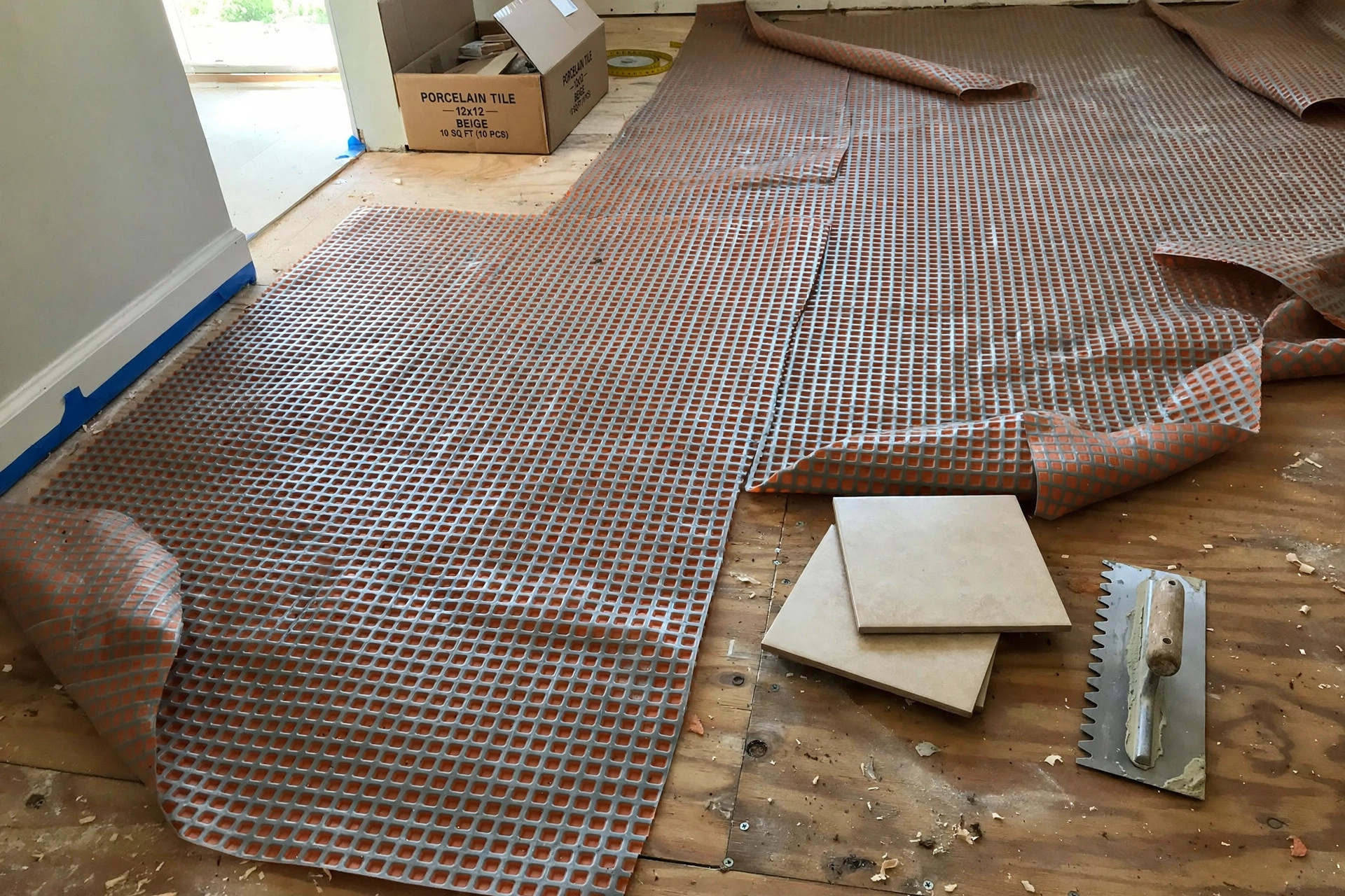 uncoupling membrane for tile floors reviews: Uncoupling membrane underlayment being installed beneath ceramic tile in a home bathroom