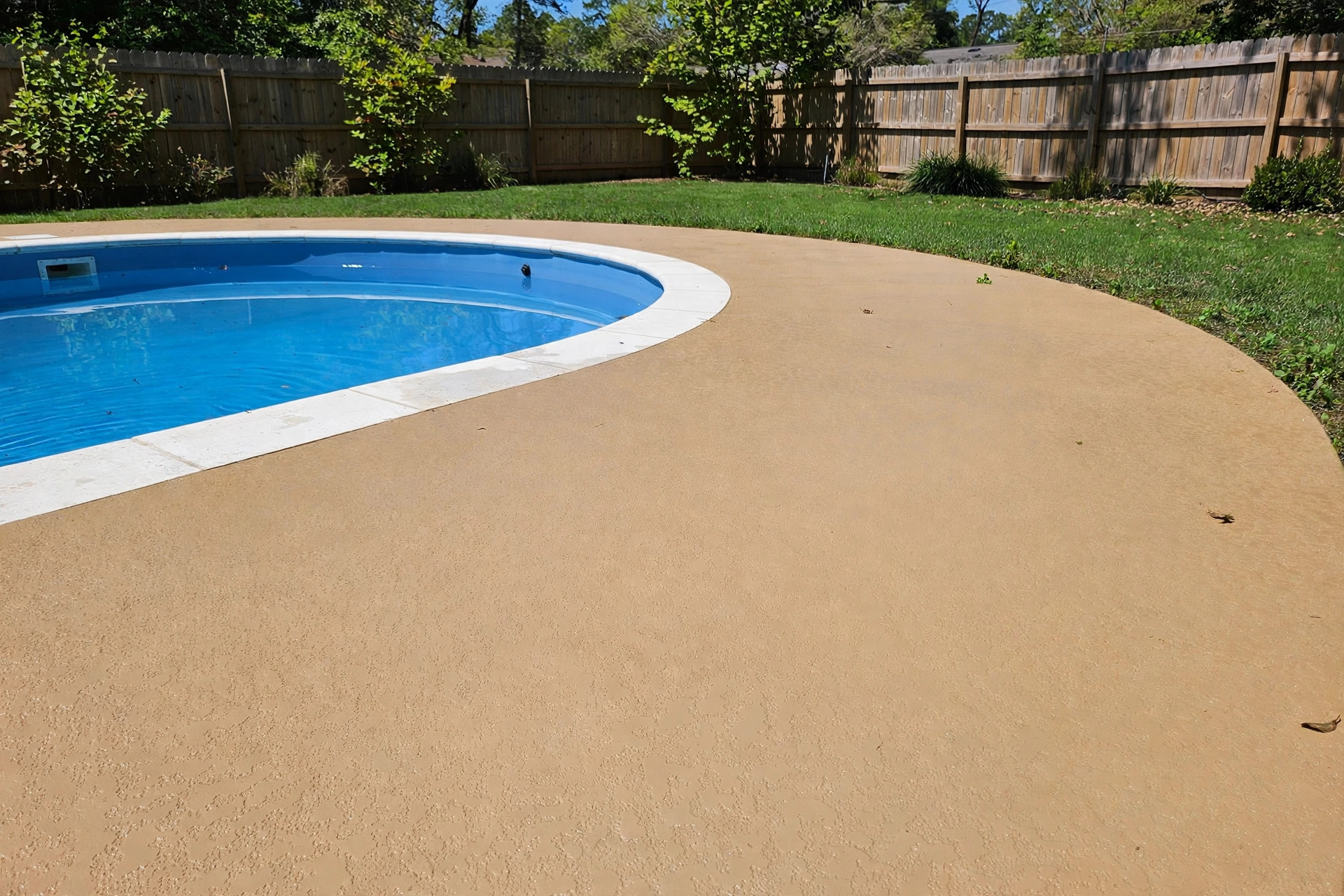 Freshly resurfaced concrete pool deck around a backyard pool, focus keyword pool deck resurfacing options and costs usa
