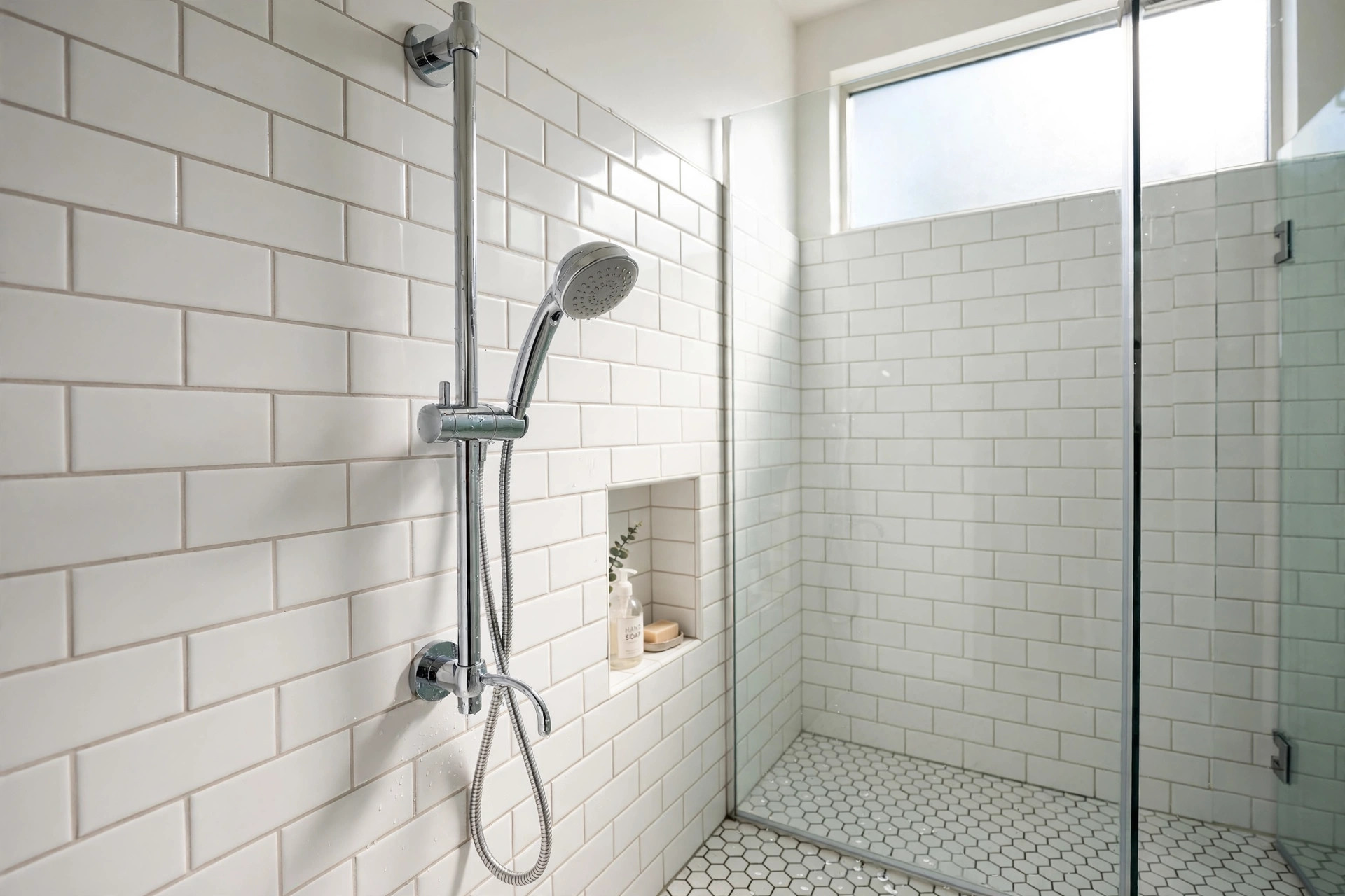 handheld shower head with slide bar reviews: A handheld shower head resting in its holder on a chrome slide bar in a tiled shower