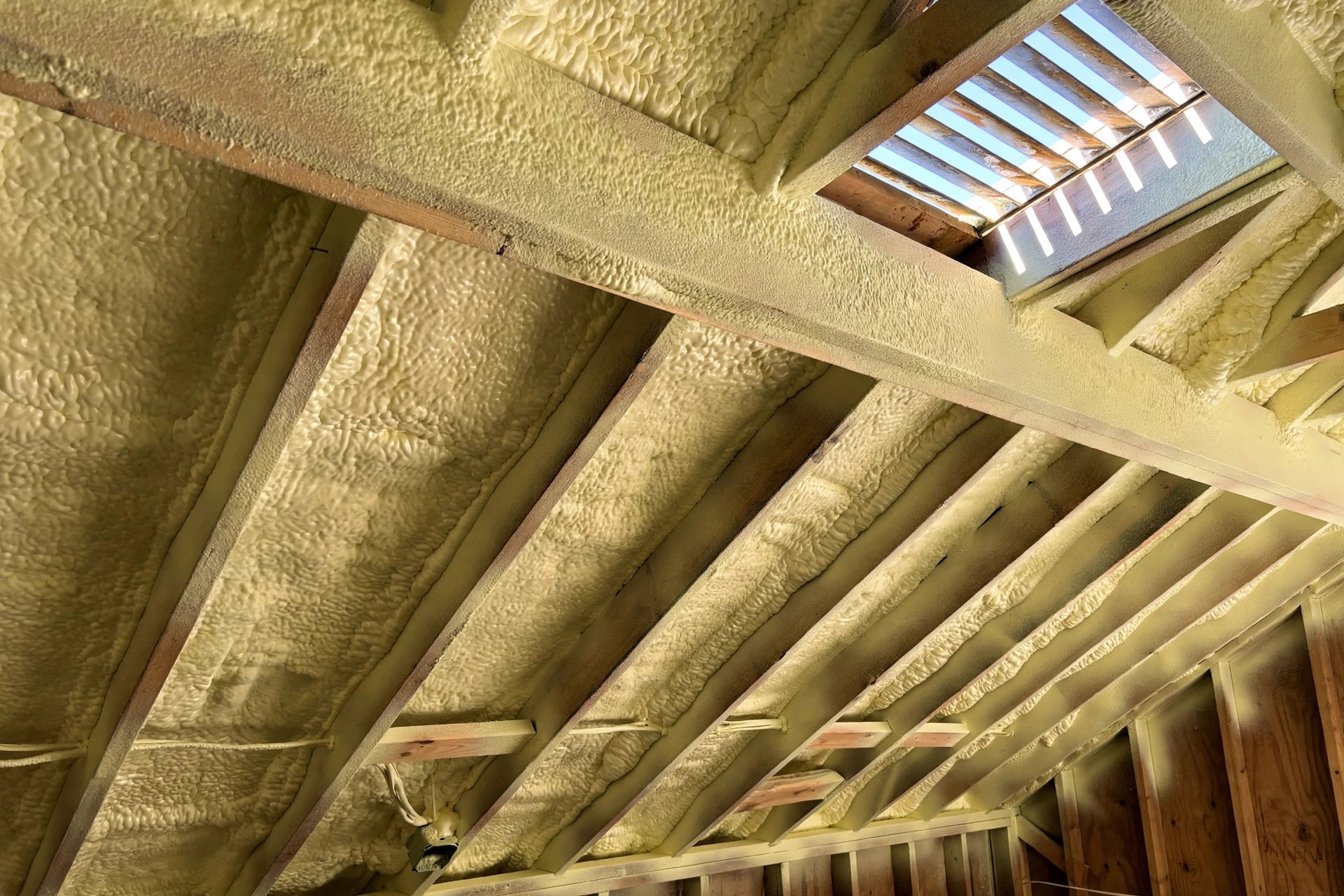 spray foam insulation cost per square foot: Fresh closed cell spray foam on attic roof deck, showing insulation cost per square foot