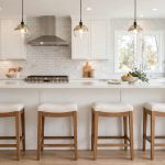 Kitchen island seating buying guide USA: four wooden counter stools with upholstered seats at a white kitchen island with quartz countertop in a bright American kitchen
