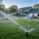 Lawn sprinkler heads watering a green yard during a sprinkler system repair service near me visit